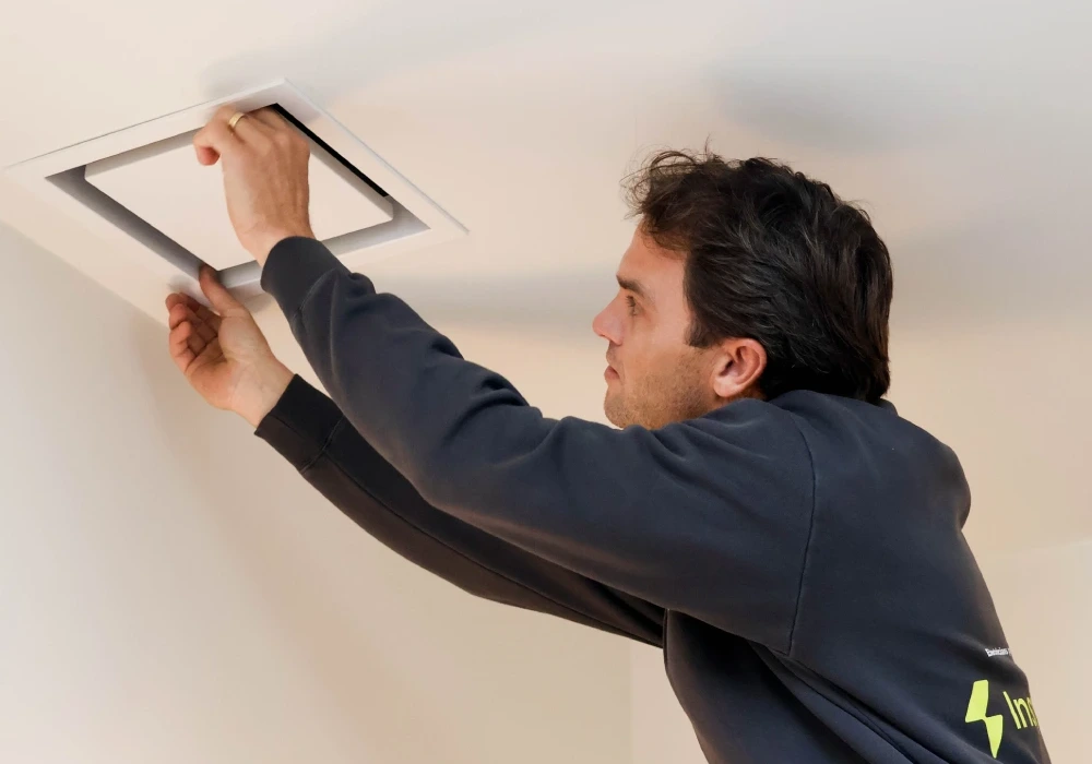 Electrician installing a smoke alarm in a Newcastle home